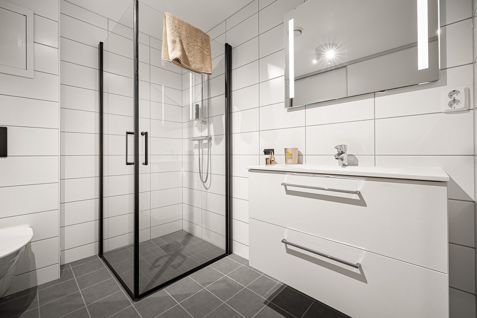 Badet er helfliset med lyse og tidløse fliser på veggene, og mørkere fliser på gulvet som har elektriske varmekabler. Galleribilde