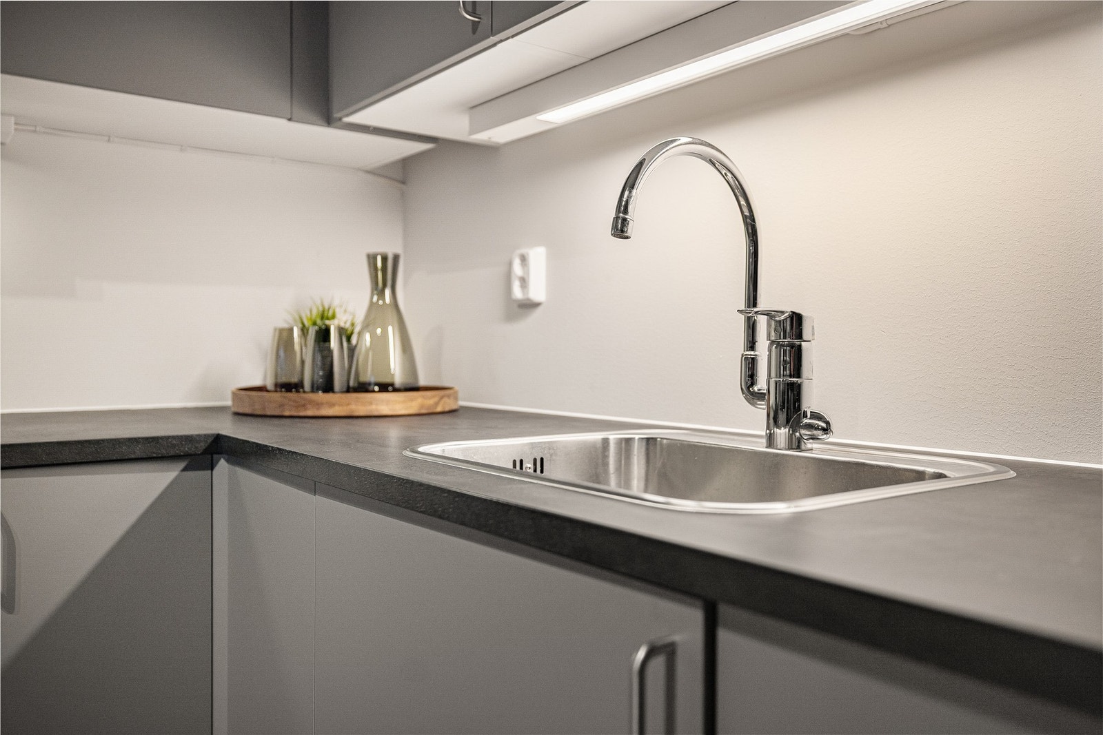 Mørk benkeplate står fint til både den grå kjøkkeninnredningen og veggen. Galleribilde