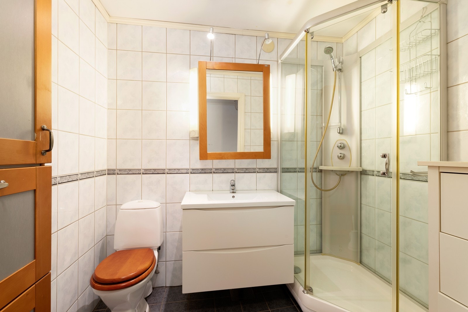 Helfliset bad innredet med vegghengt servantmøbel, stående klosett og dusjkabinett. Galleribilde