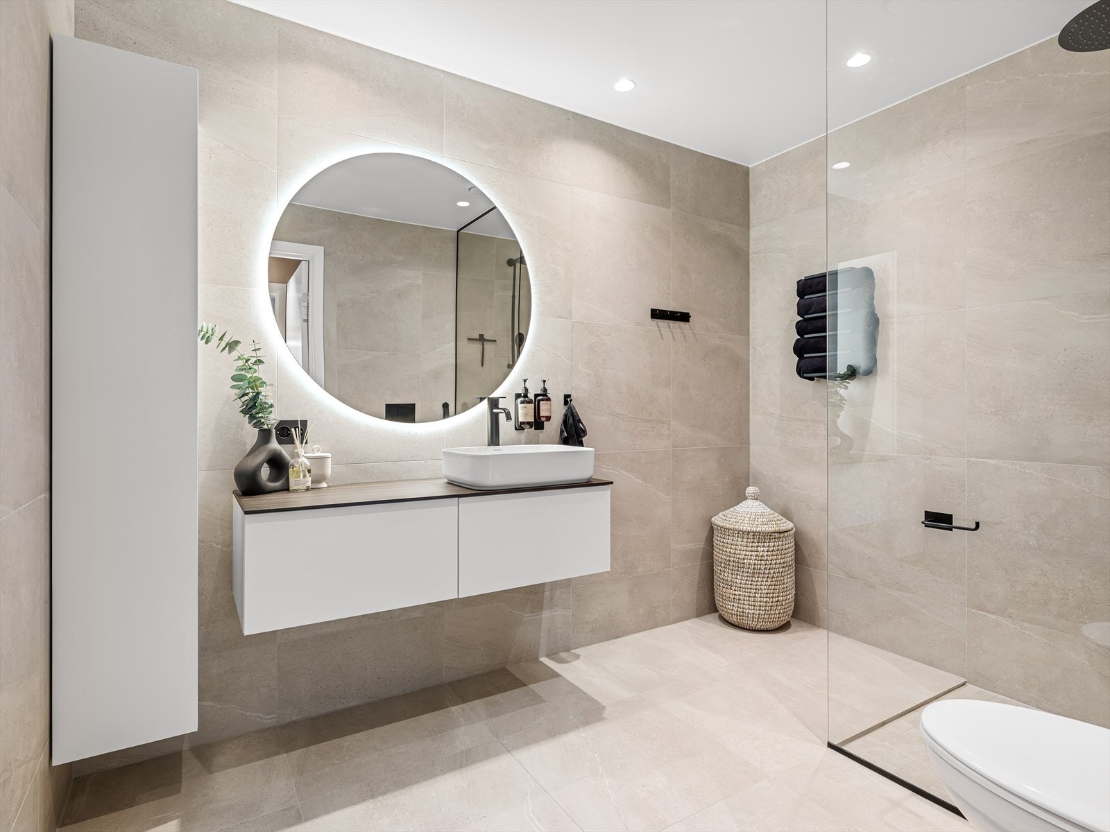 Ekstra lagringsplass i vegghengt skap. Rundt speil med belysning. Spotter i tak og varmekabler i gulv. Galleribilde