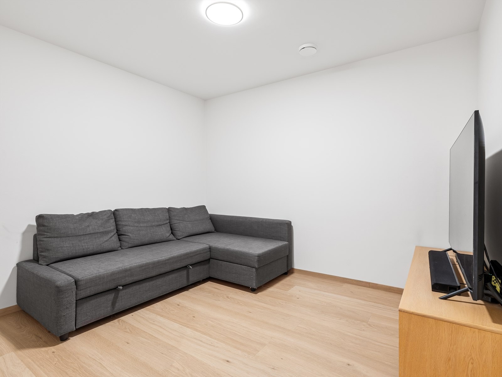 Hobbyrom innredet som en ekstra tv-stue/kontor. Lyse vegger og en-stavs laminat på gulv. Galleribilde