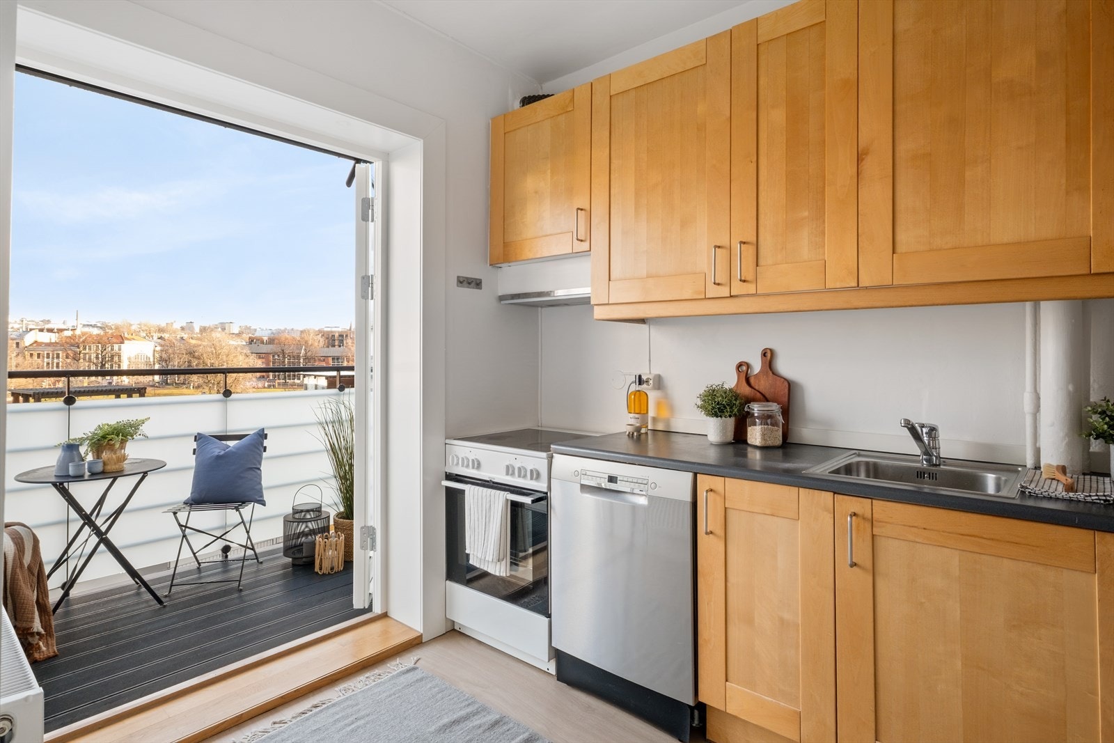 Profilert innredning fra IKEA, lyslist, laminat benkeplate med nedfelt stålkum, komfyr, oppvaskmaskin, kjøl/frys. Det er kjøkkenventilator med avtrekk ut. Galleribilde