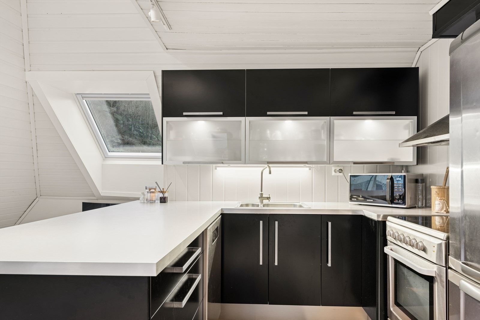 Pent kjøkken med glatte fronter og laminert benkeplate. God skap- og benkeplass og innredning slik at matlagingen forenes med sosialt samvær. Galleribilde