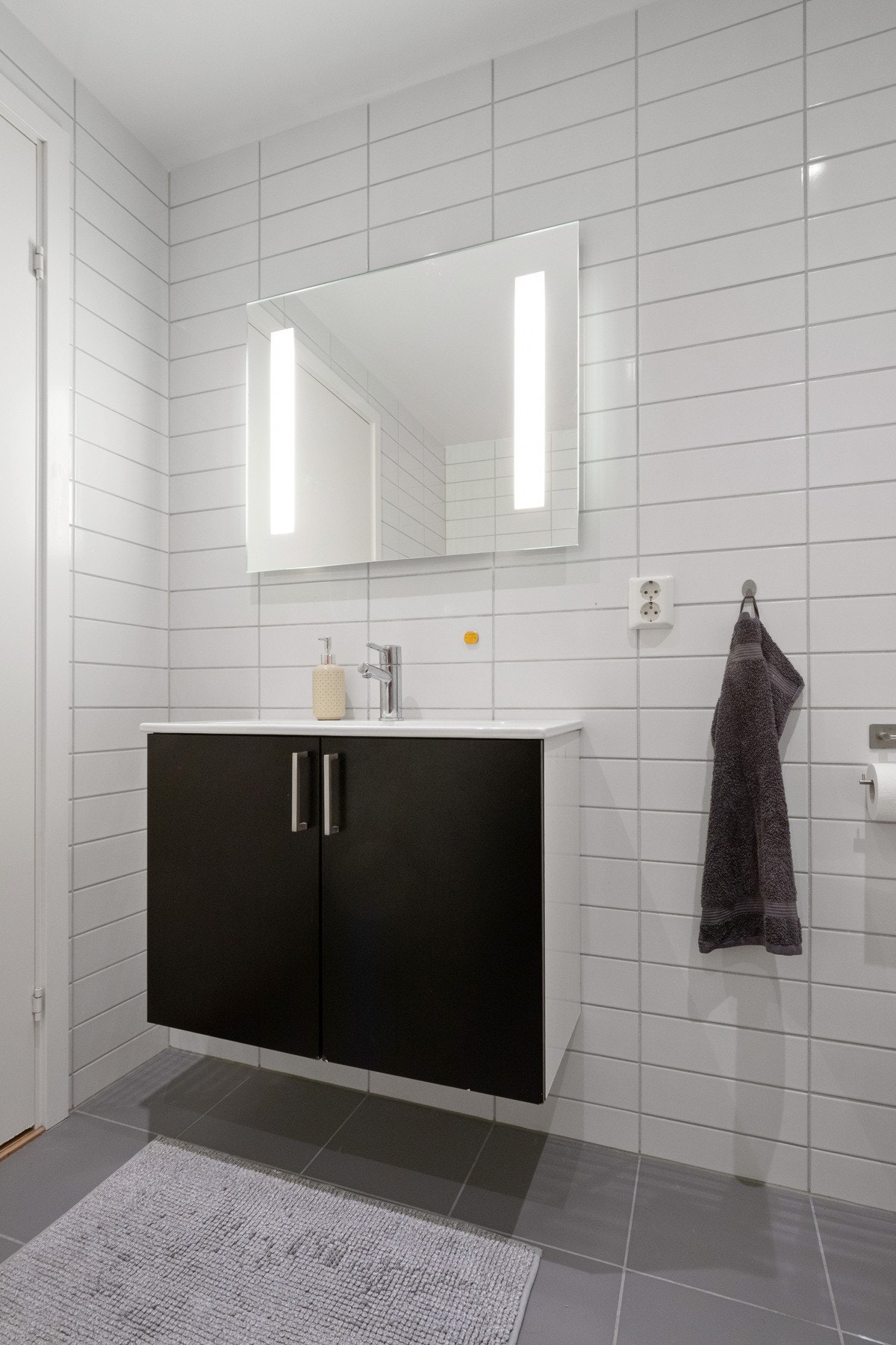 Innredningen byr på god oppbevaringsplass bak mørke skapfronter og det er for øvrig både heldekkende servant og speil med integrert belysning Galleribilde