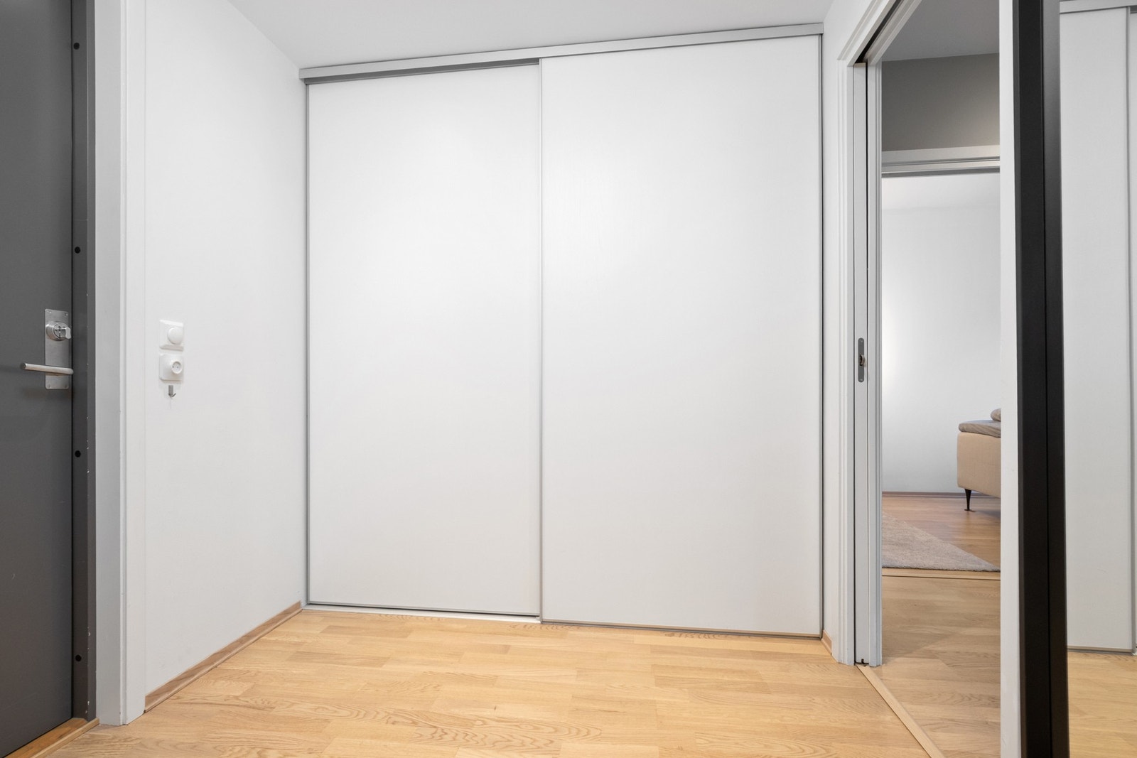 Nyere parkett på gulvet og downlights i himlingen skaper en stilren helhet, mens den mørke inngangsdøren gir en fin kontrast til de hvitmalte veggene. Romslig skyvedørsgarderobe for oppbevaring av yttertøy Galleribilde