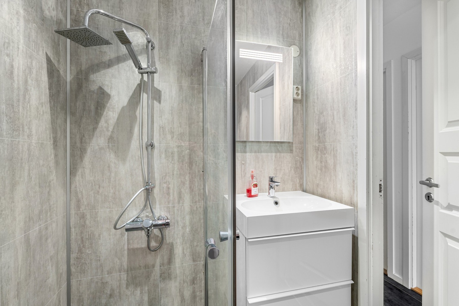 Badet har flislagt gulv og er utstyrt med innfellbare dusjdører. Galleribilde