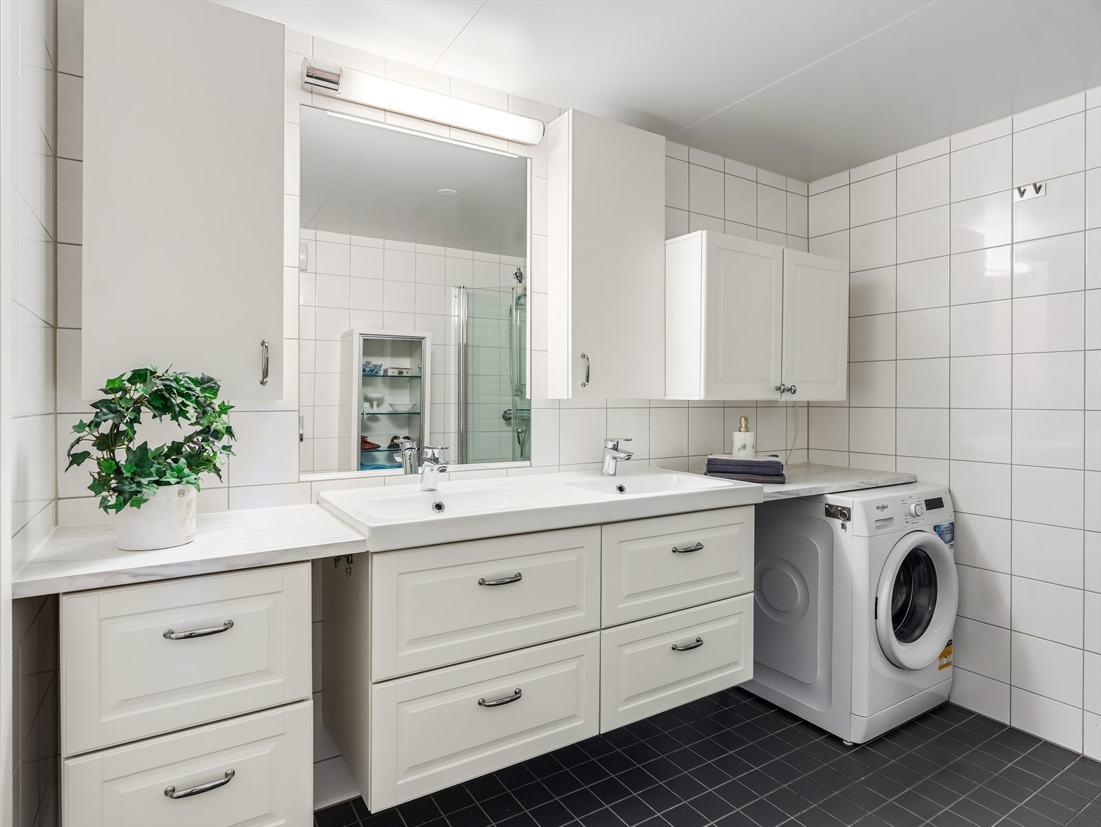 Baderommet har flislagte overflater og elektriske varmekabler i gulvet. Rommet er videre innredet med dusj på gulv med dører i herdet glass, veggfestet klosett med innebygget sisterne samt servant. Galleribilde