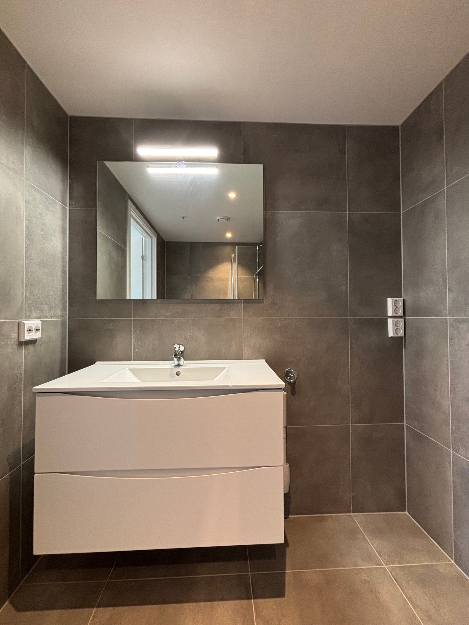 Lys vegghengt innredning med opplegg for vaskemaskin ved siden av Galleribilde