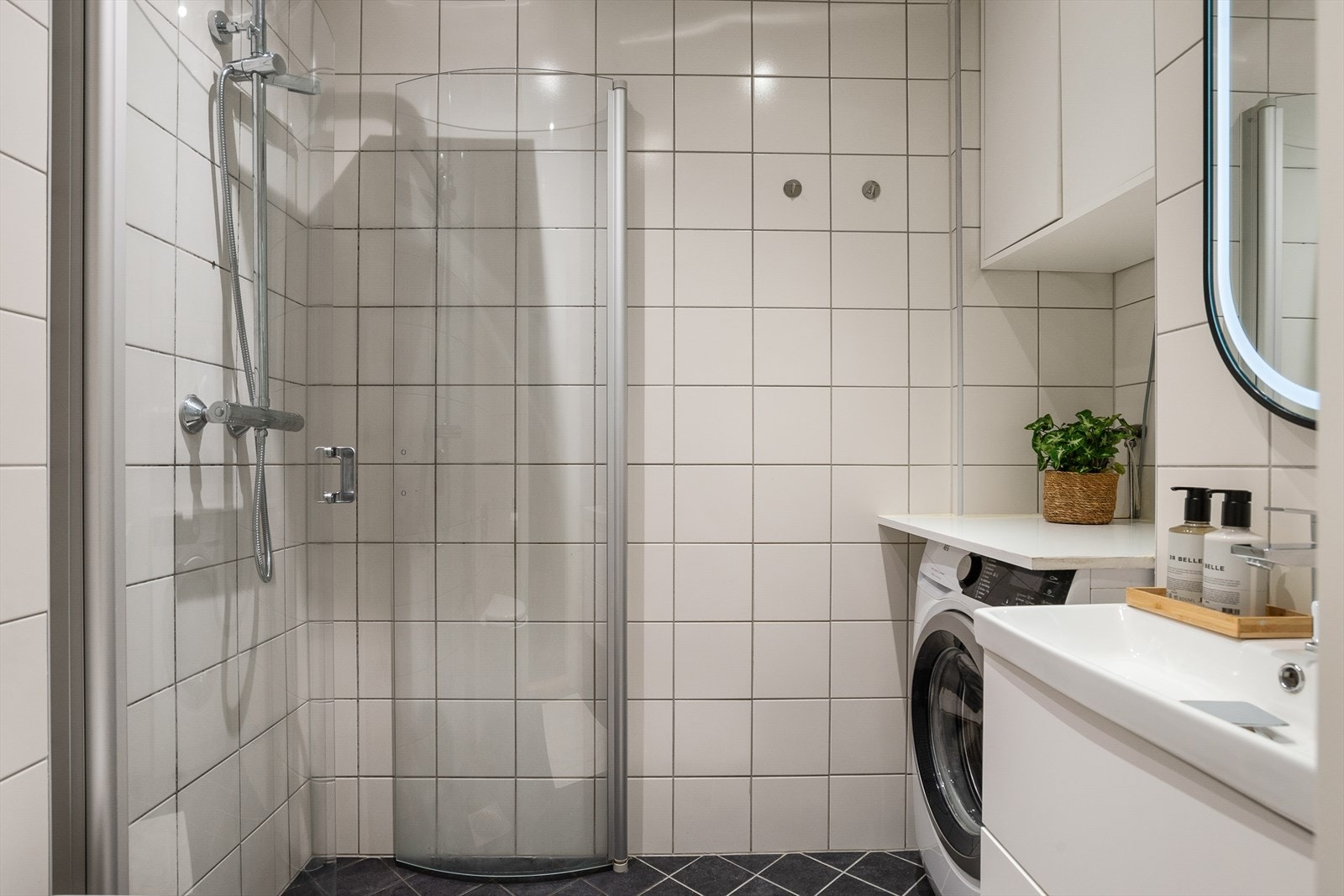 Lyst bad med flislagte overflater og varmakalber i gulvet. Taket er malt og utstyrt med dimbare downlights som gir fleksibel belysning. Galleribilde