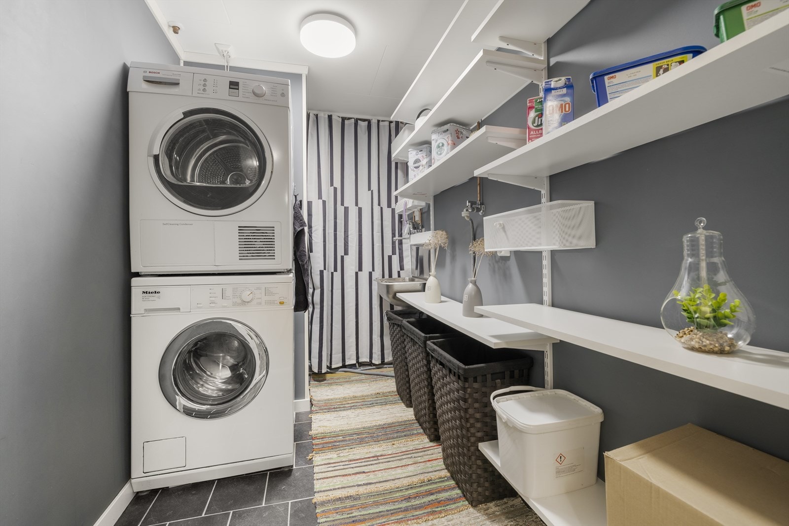 Separat og funksjonelt vaskerom med flislagt gulv og opplegg for vaskemaskin. Galleribilde
