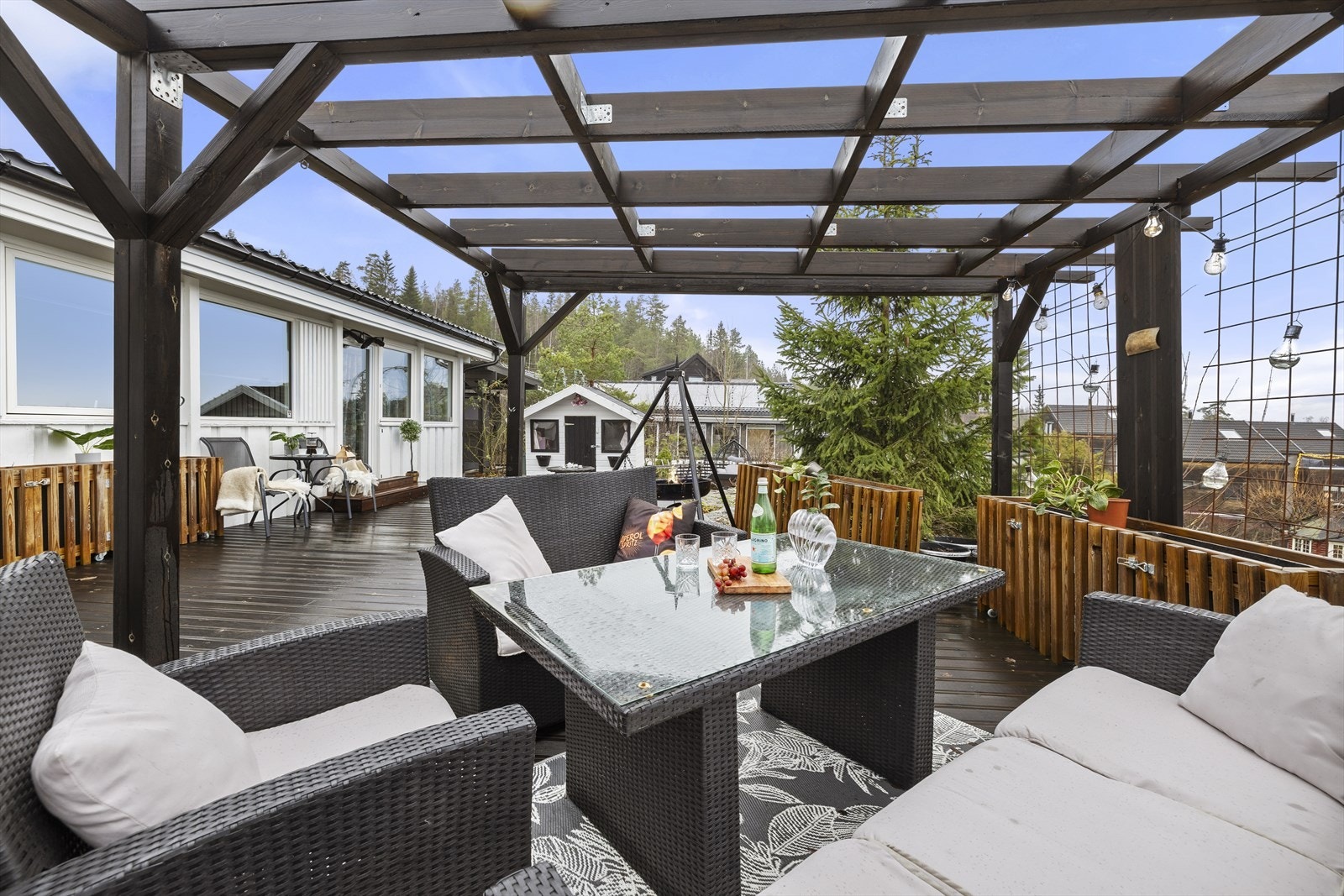 En frittstående, overbygd pergola i tre skaper en lun sone på terrassen. Galleribilde