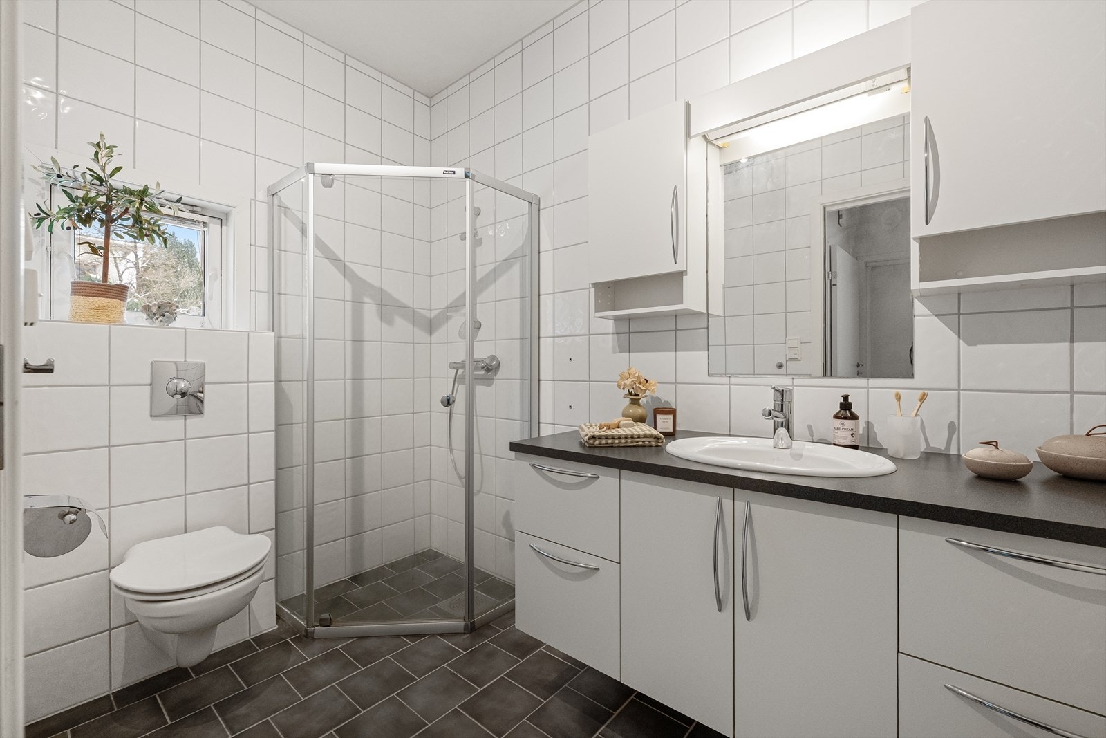 Helfliset bad utført dusjnisje, vegghengt toalett og servant med god skapplass. Galleribilde