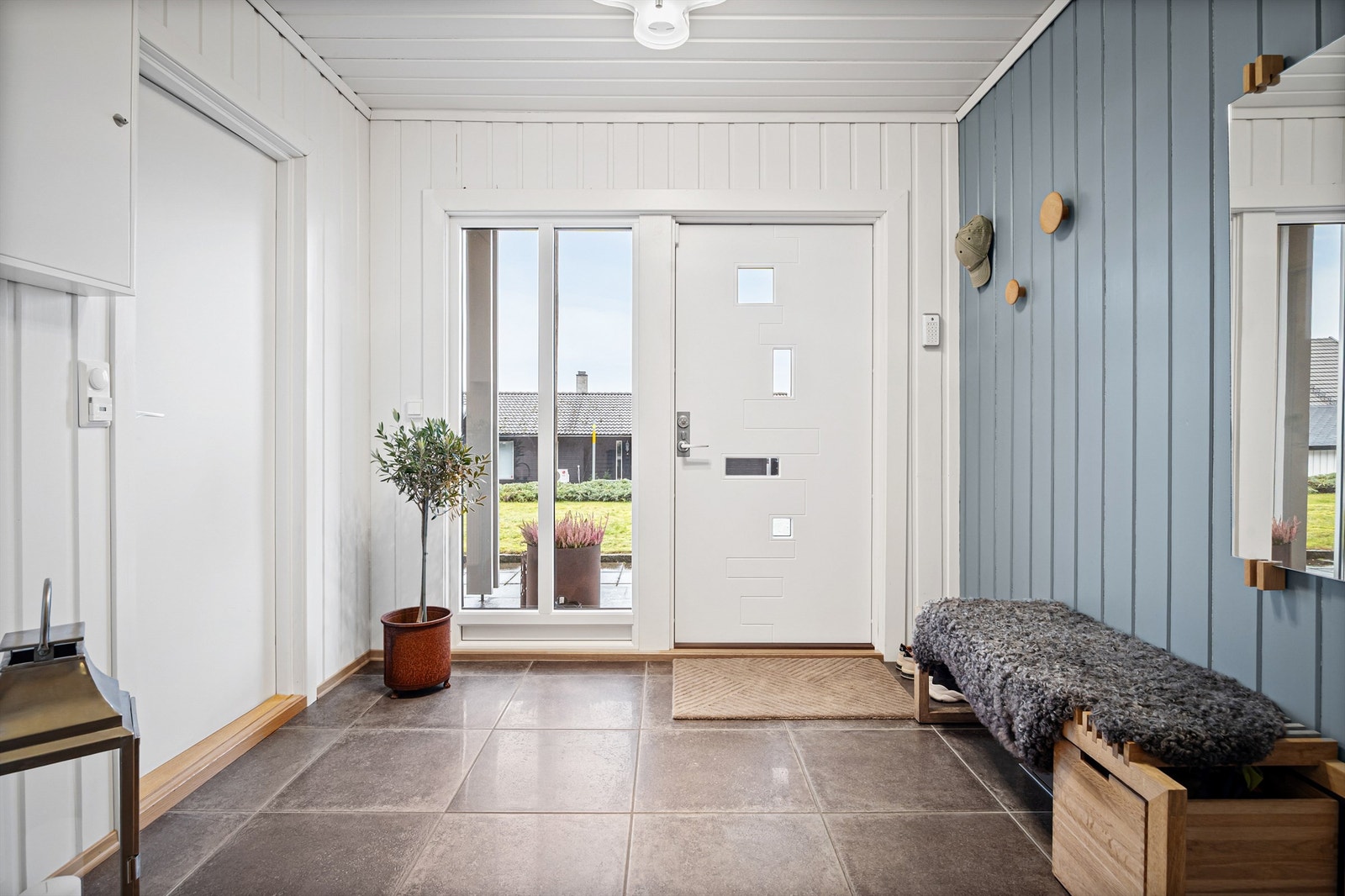 Overbygget inngangsparti i underetasjen med adkomst via hellelagt gangvei. Galleribilde