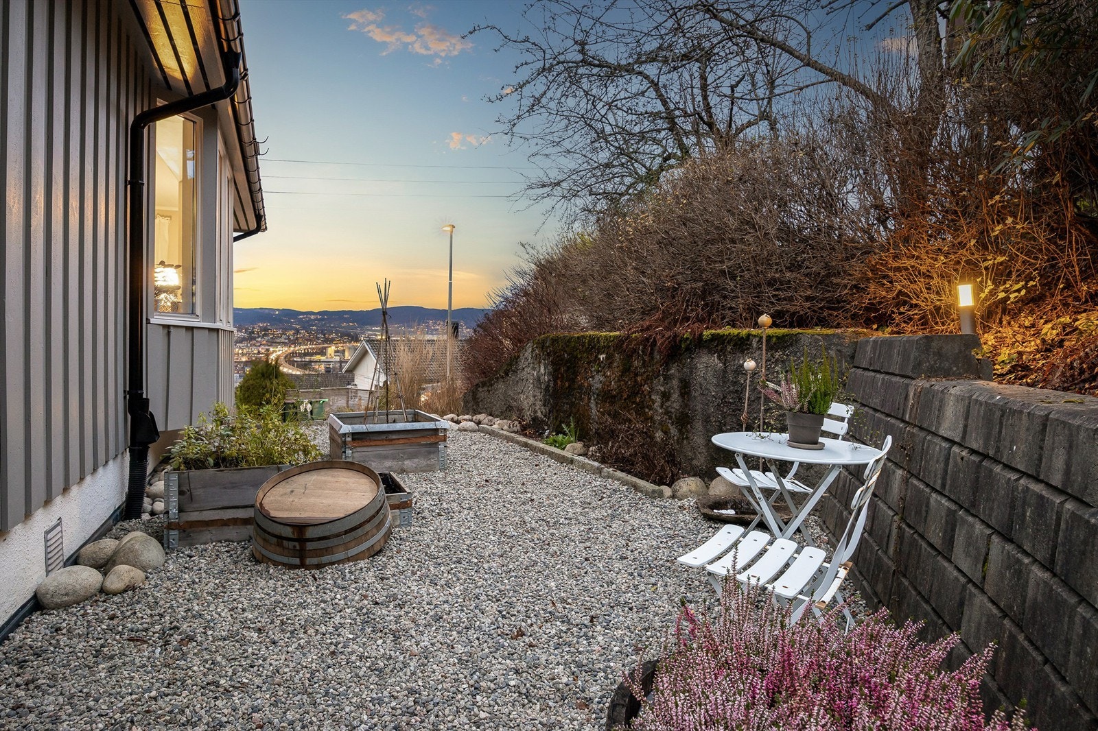 Gruset uteplass på siden av boligen, ideell for en liten sittegruppe. Galleribilde