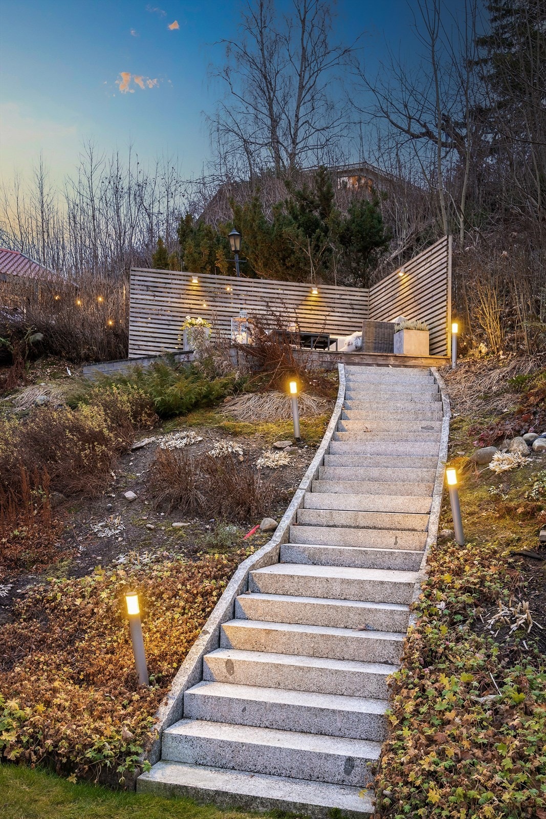 En utvendig trapp i naturstein leder opp til en egen platting med levegg. Galleribilde