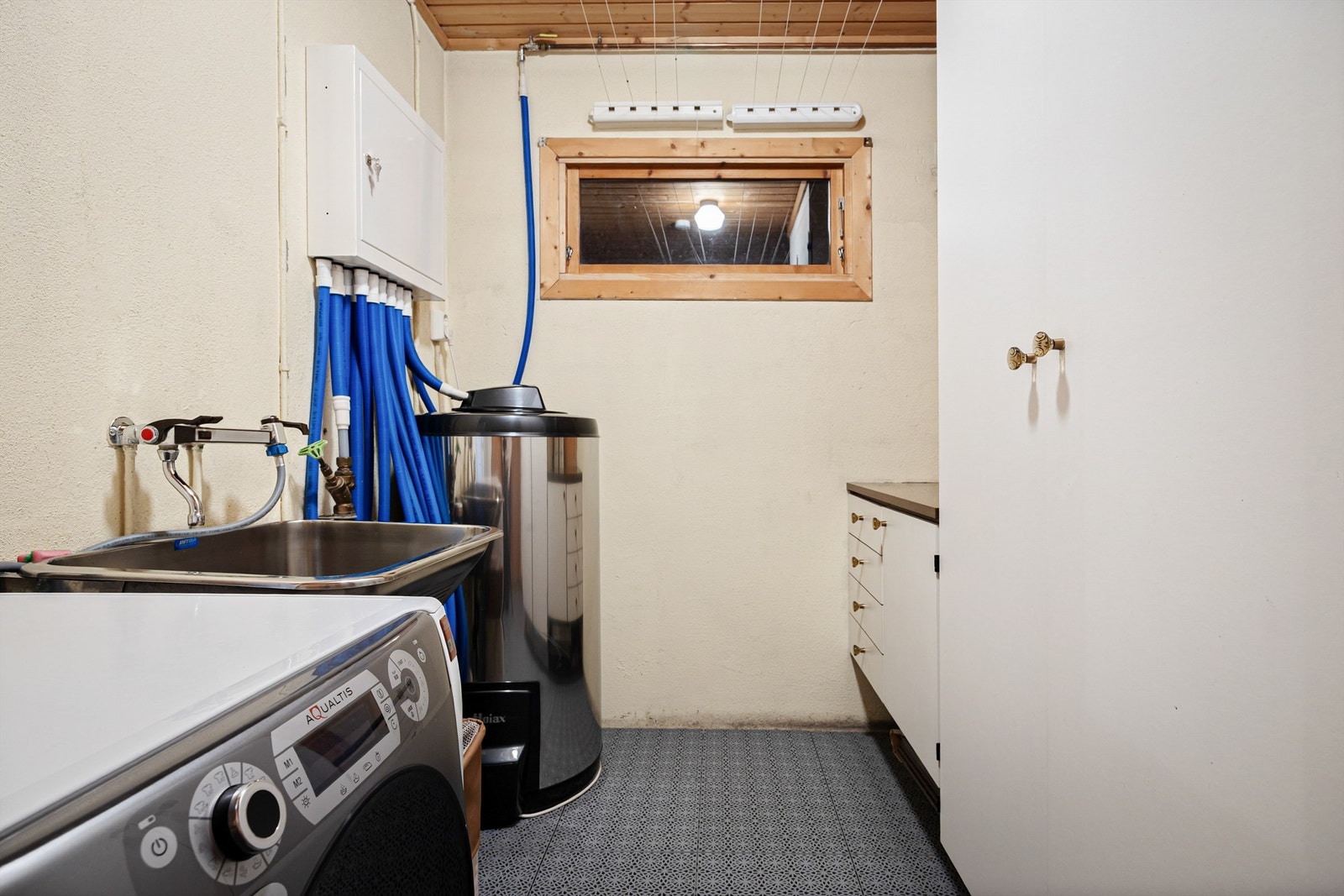 Praktisk vaskerom med utslagsvask, vaskemaskin og 200L varmtvannsbereder. Galleribilde