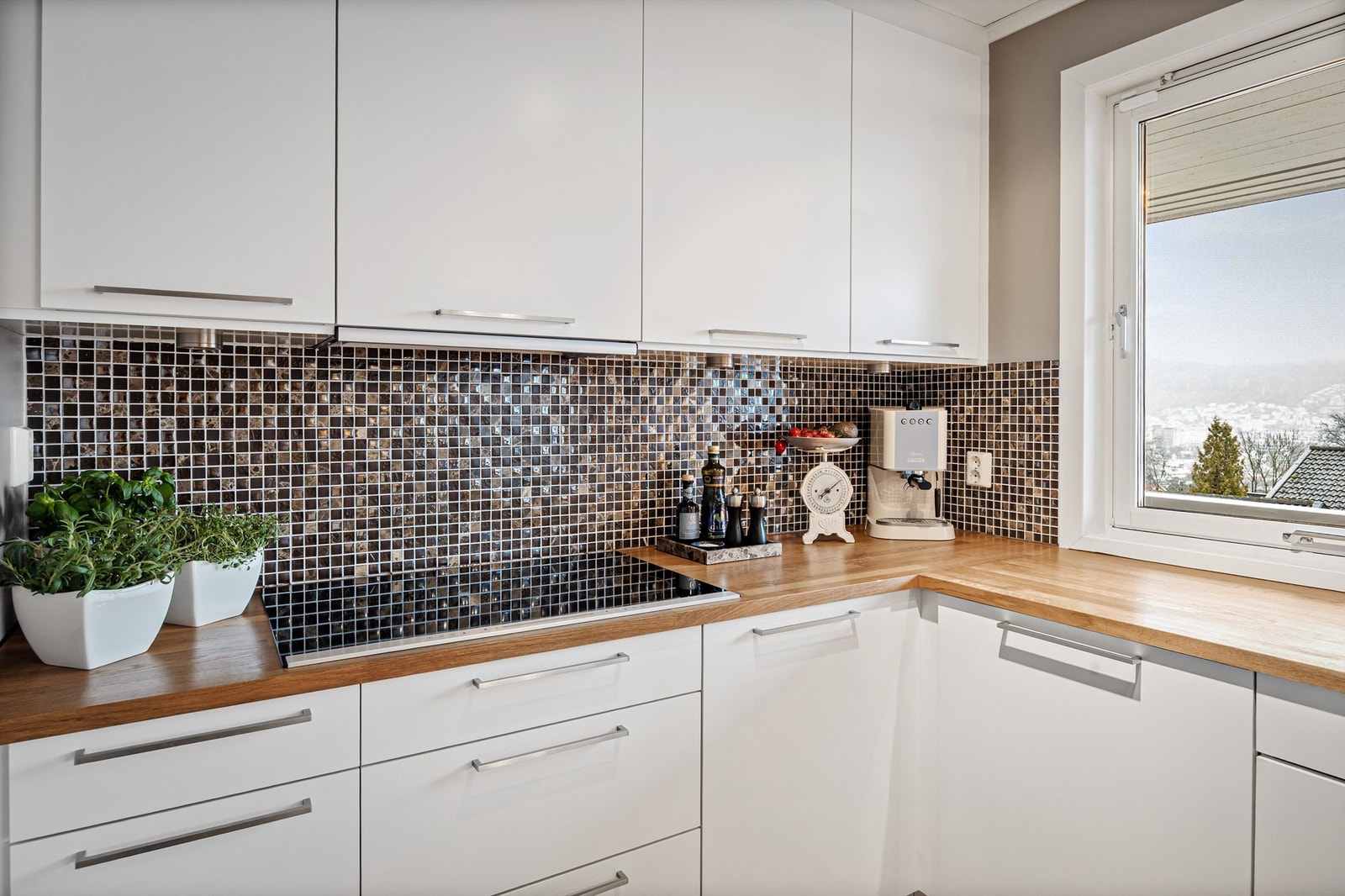 Flislagte felt over benken og nedfelt platetopp understreker kjøkkenets funksjonalitet. Galleribilde