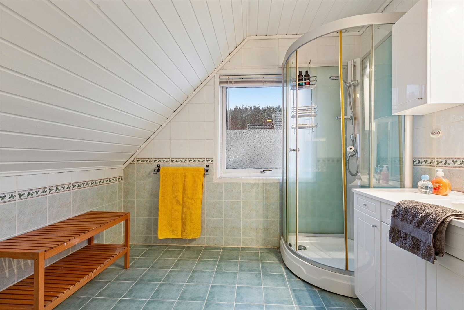 Baderommet er flislagt og er utstyrt med dusjkabinett, WC og nedfelt servant med underskap Galleribilde