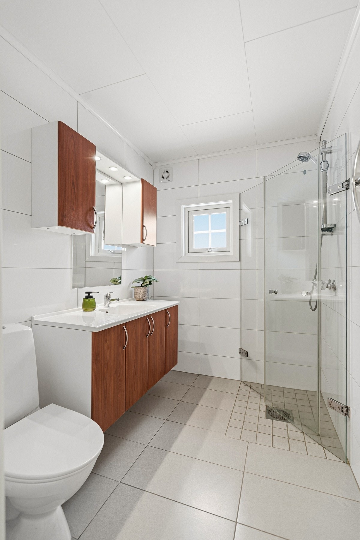 Badet er flislagt og utstyrt med varmekabler i gulv, servant med innredning, toalett og dusjløsning. Badet fremstår som funksjonelt og godt ivaretatt. Galleribilde