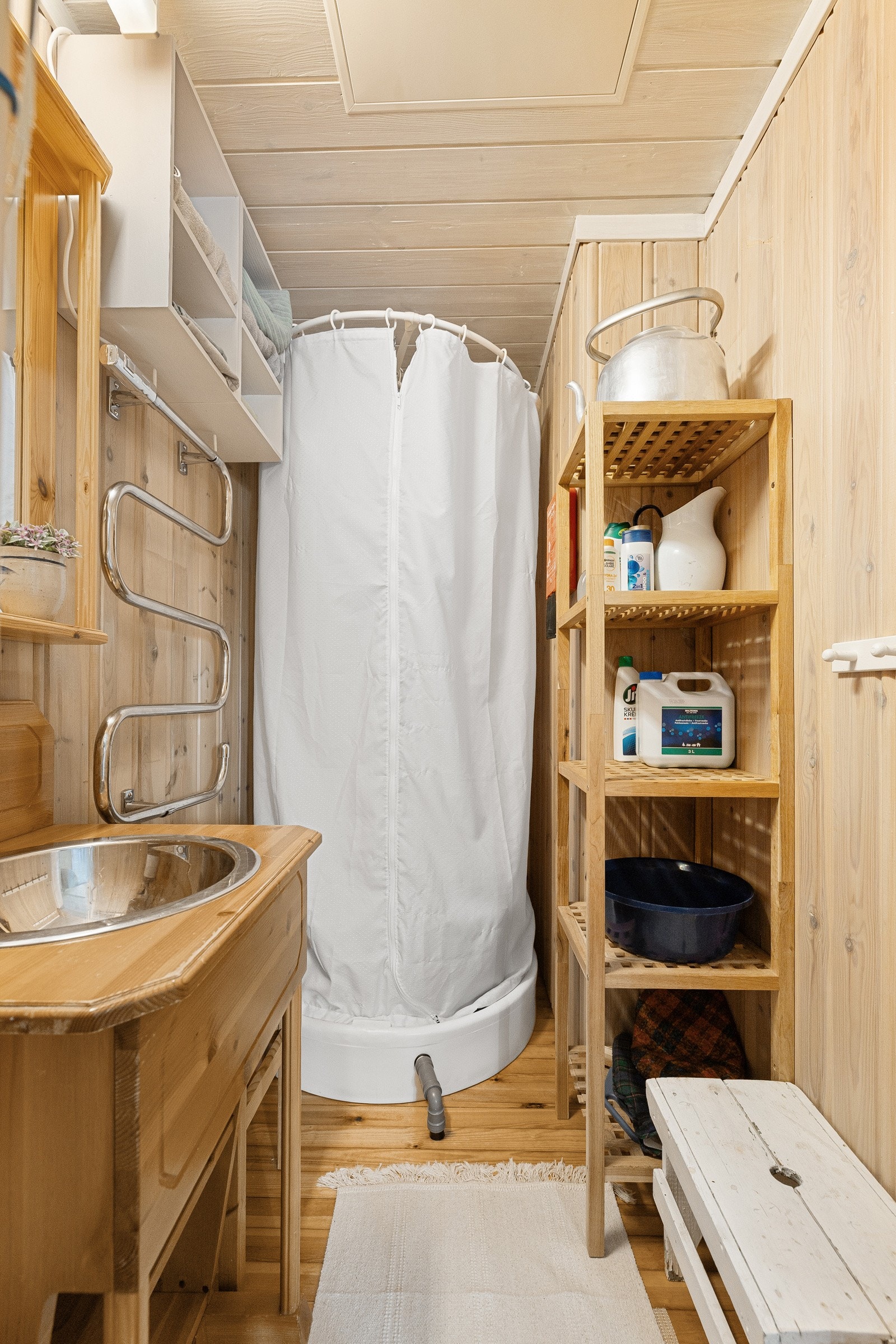 Badet er praktisk innredet med dusjløsning bestående av kar og kabinett med rundt forheng. Dusjkabinettet har egen tank for påfylling av varmt vann og betjenes med manuell pumpe. Galleribilde