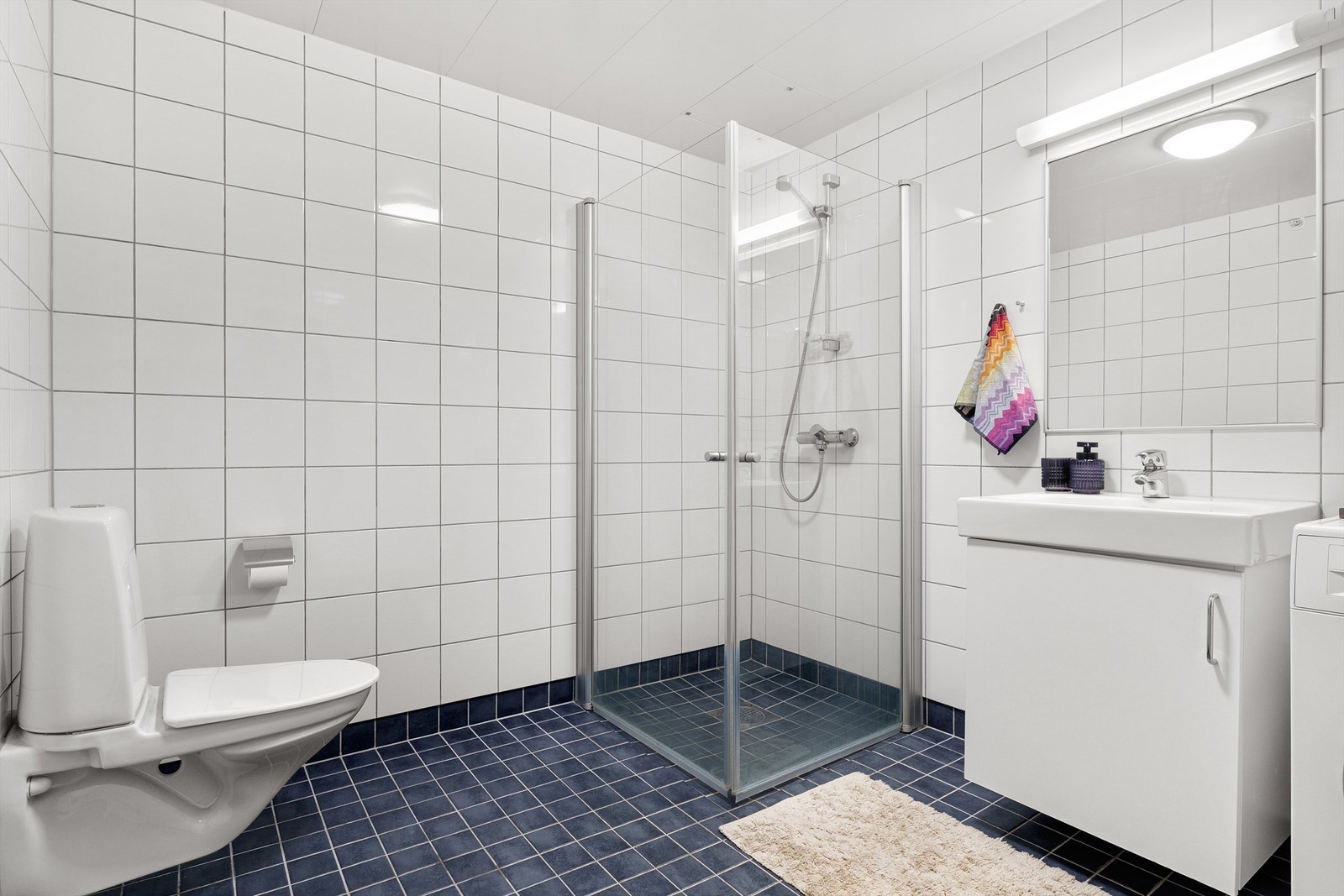 Helfliset bad med vannboren gulvvarme, vegghengt toalett, baderomsmøbler og dusj med innsvingbare dusjvegger Galleribilde