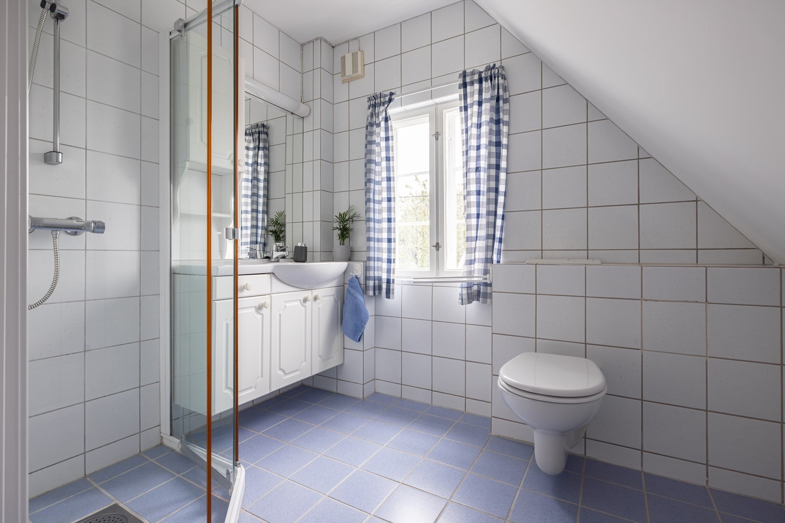 Flislagt bad i 2. etasje innredet med servant, veggmontert toalett og dusjvegger/hjørne. Galleribilde