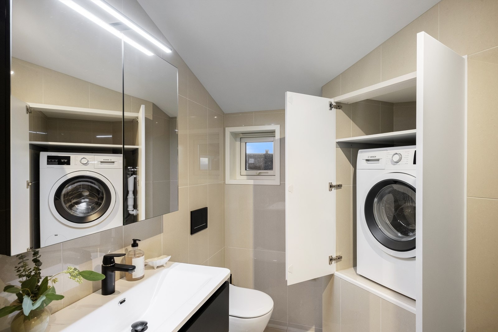 Opplegg for vaskemaskin i praktisk skapnisje - vaskemaskin medfølger. Baderommet byr på rikelig med oppbevaringsplass, både med vegg- og benkeskap samt praktisk plassbygget hylleløsning. Galleribilde