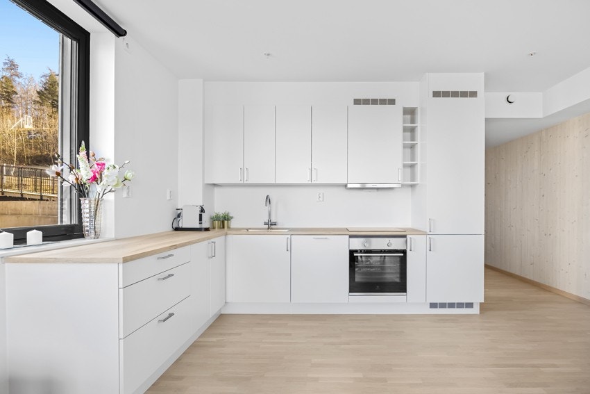 Pent og lyst kjøkken med glatte fronter og en benkeplate i laminat. Galleribilde