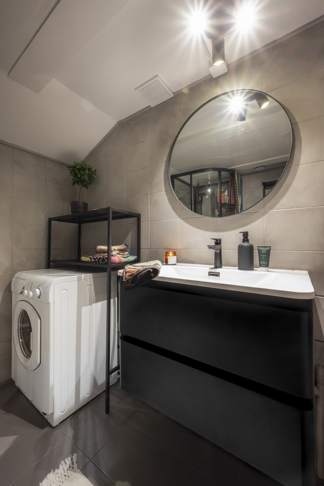 Badet har elektrisk gulvvarme og er innredet med toalett, servant nedfelt i innredning og dusjkabinett. Rommet har naturlig avtrekk. Galleribilde