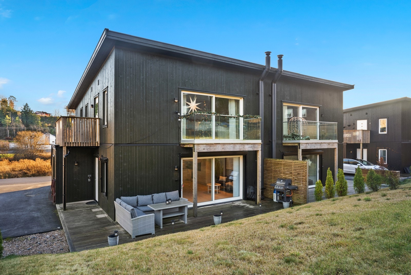 Moderne arkitektur med mørk, stående trekledning og store vindusflater. Galleribilde