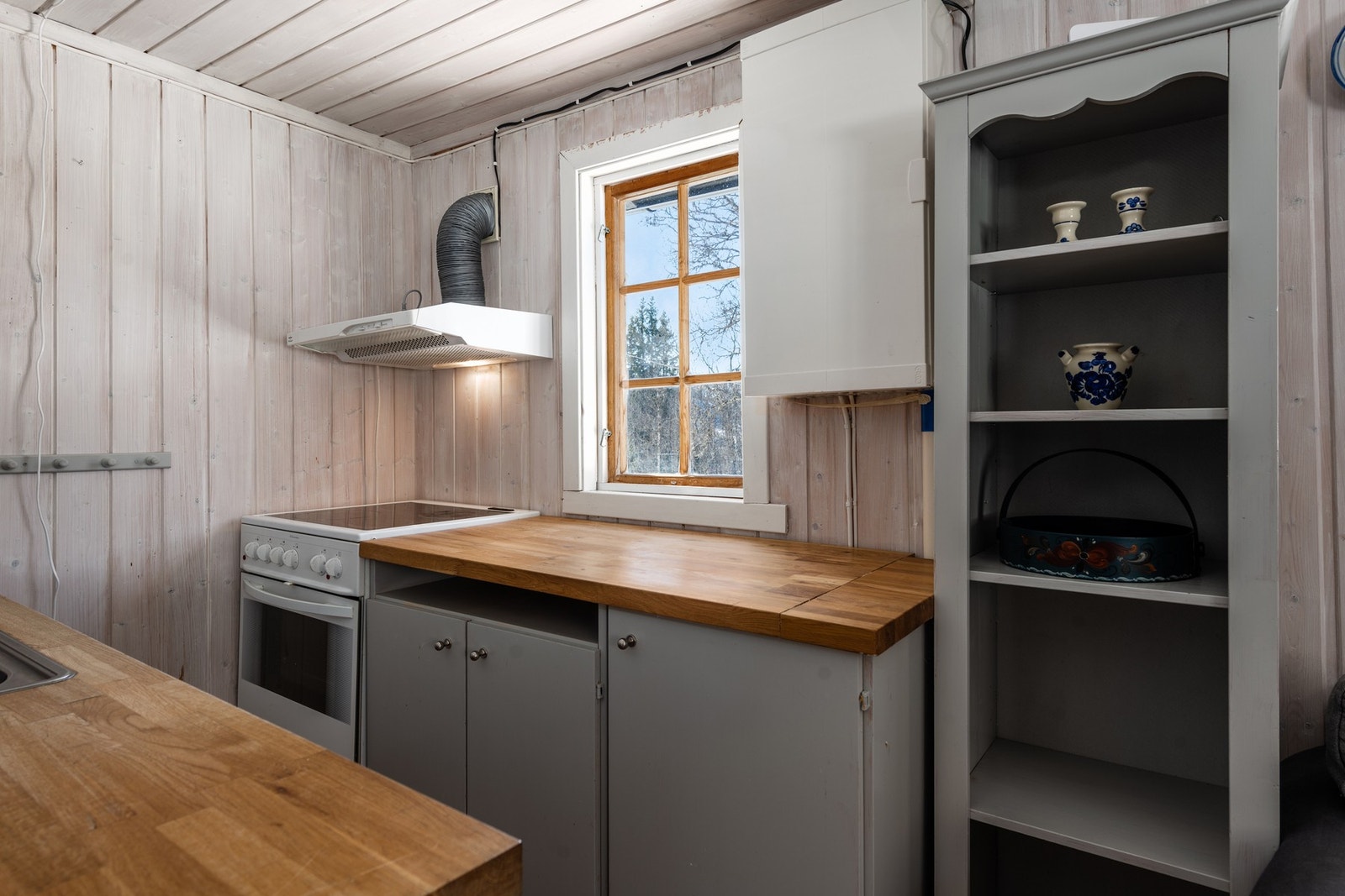 Kjøkken: Lakket tregulv og beiset trepanel på vegger. Kjøkkeninnredning med overskap og underskap, heltre skapdører og heltre benkeplate med oppvaskkum. Komfyr og kjøeskap. Det er kjøkkenventilator med avtrekk ut Galleribilde