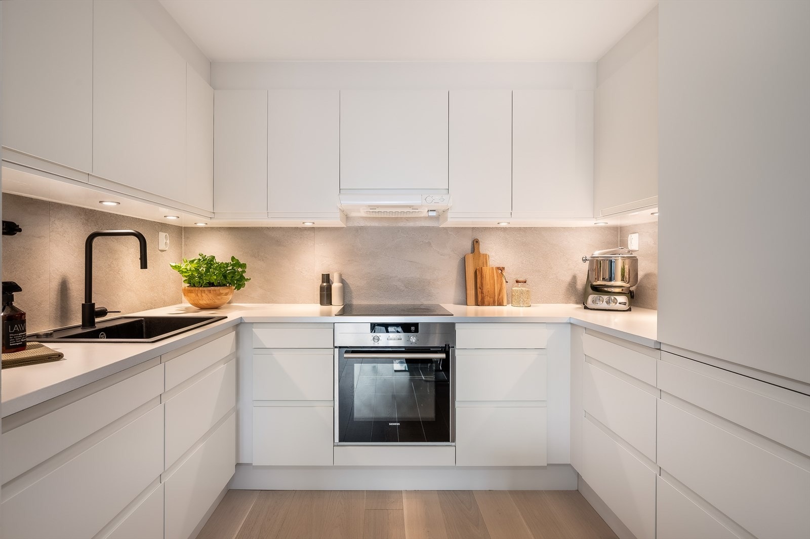 I åpen løsning mot stuen ligger kjøkkenet, som byr på rikelig med skap- og benkeplass. Kjøkkeninnredningen fra HTH er pent gjort og har glatte fronter, laminat benkeplate med nedfelt kum i kompositt og fliser på vegg. Galleribilde