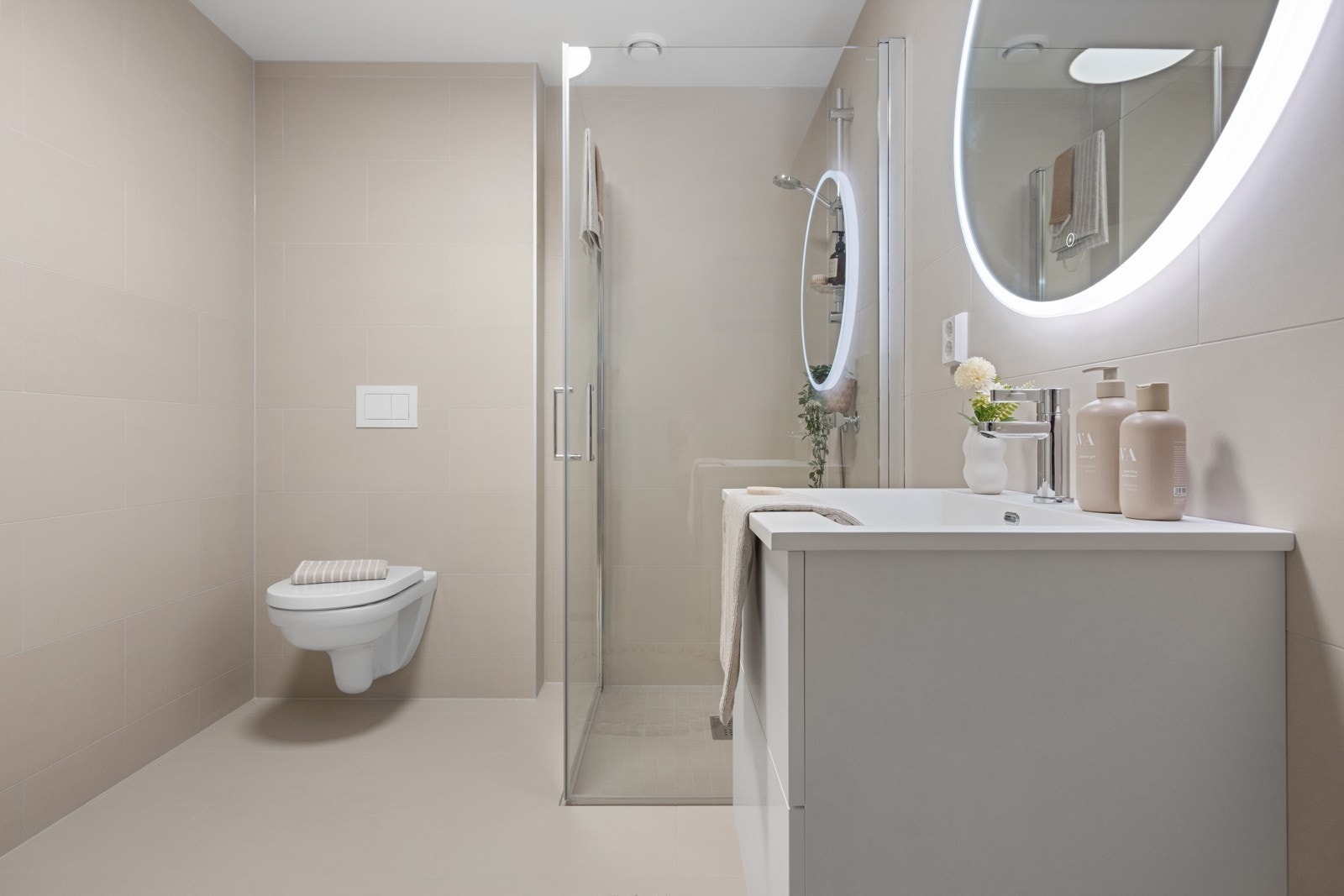 Badet er helfliset med vegghengt toalett, innglasset dusjhjørne, servant med underskap og speil med belysning. Galleribilde