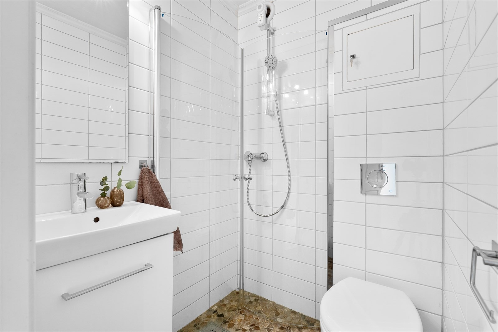 Fliselagt bad med dusjhjørne, vegghengt toalett og servant med innredning Galleribilde