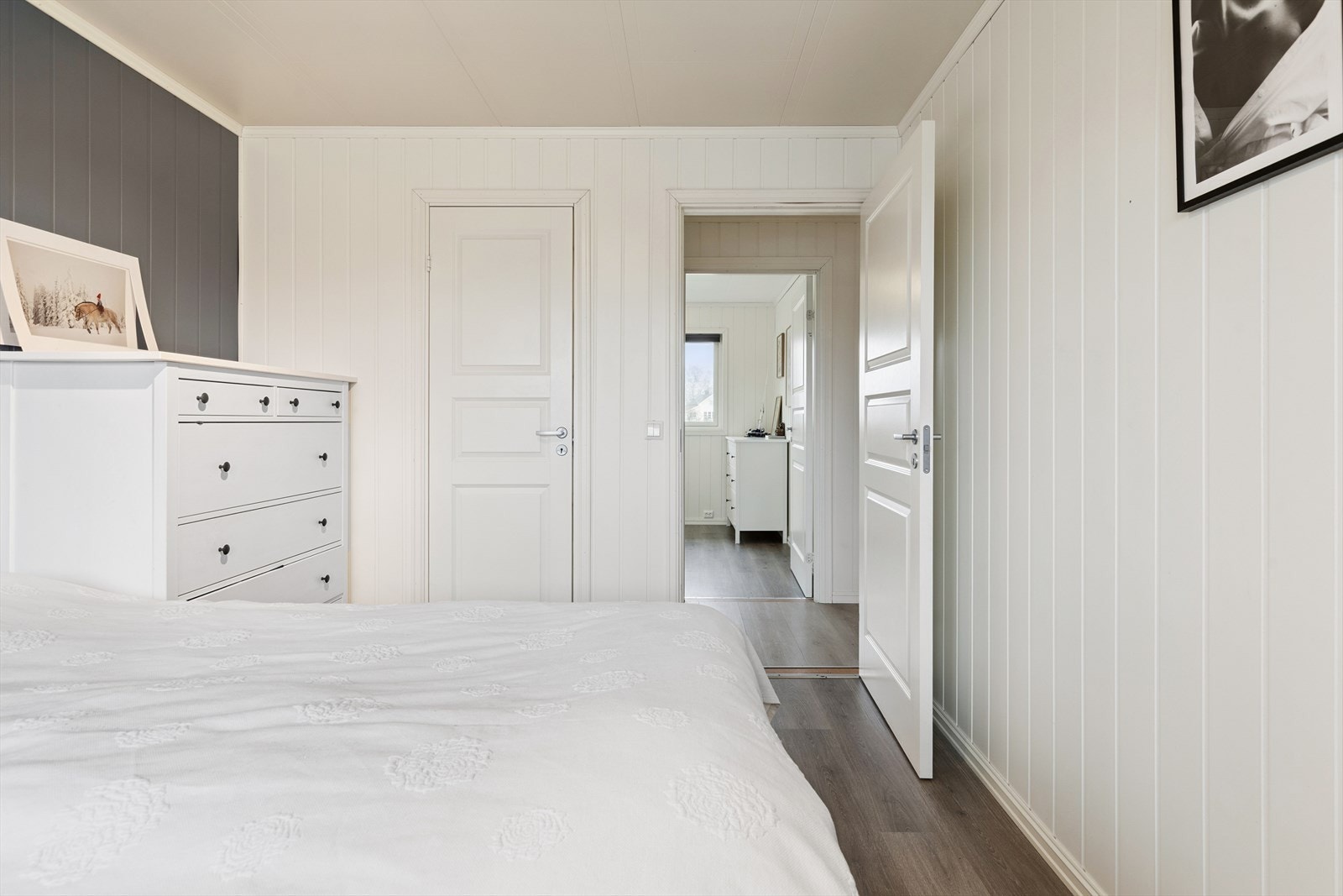 Rommet har lysmalte panelvegger og laminat på gulvet. Galleribilde