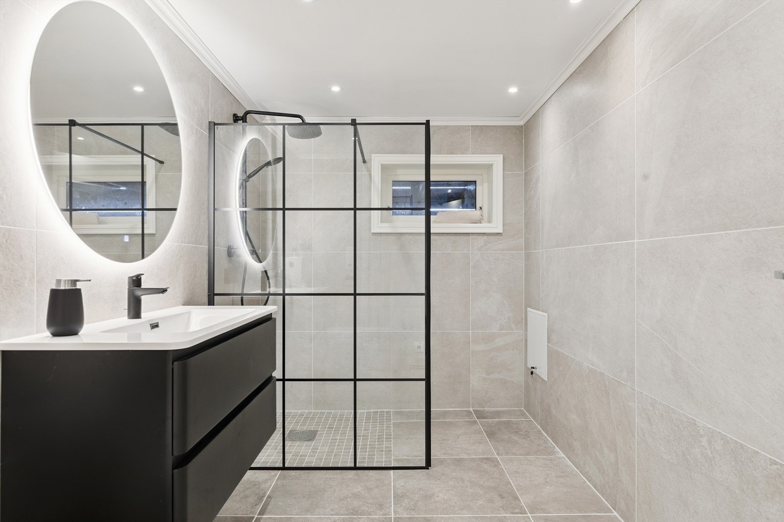 Boligen har to bad. Dette er fra underetasjen, med moderne fliser og dusjvegg i glass. Ventilasjon har TG3. Galleribilde