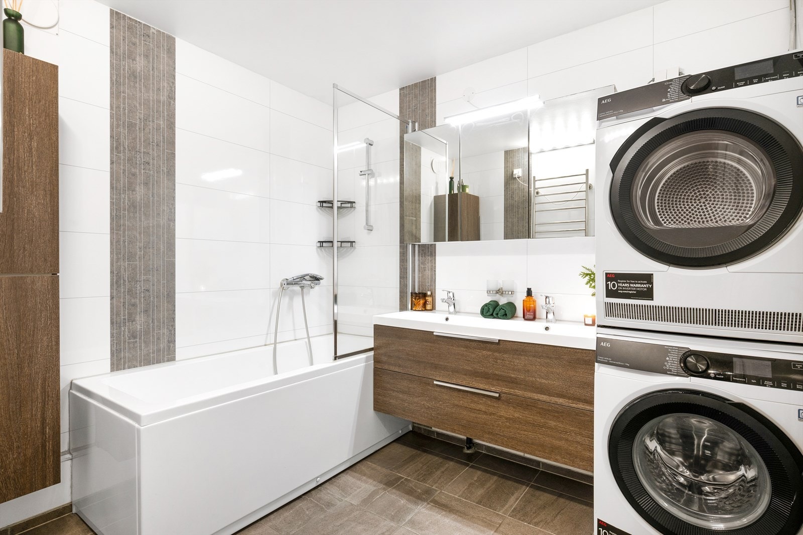 Badet er pent innredet med tidsriktig farger, heldekkende servant, speilskap med belysning, badekar og opplegg for vaskemaskin og tørketrommel. Galleribilde