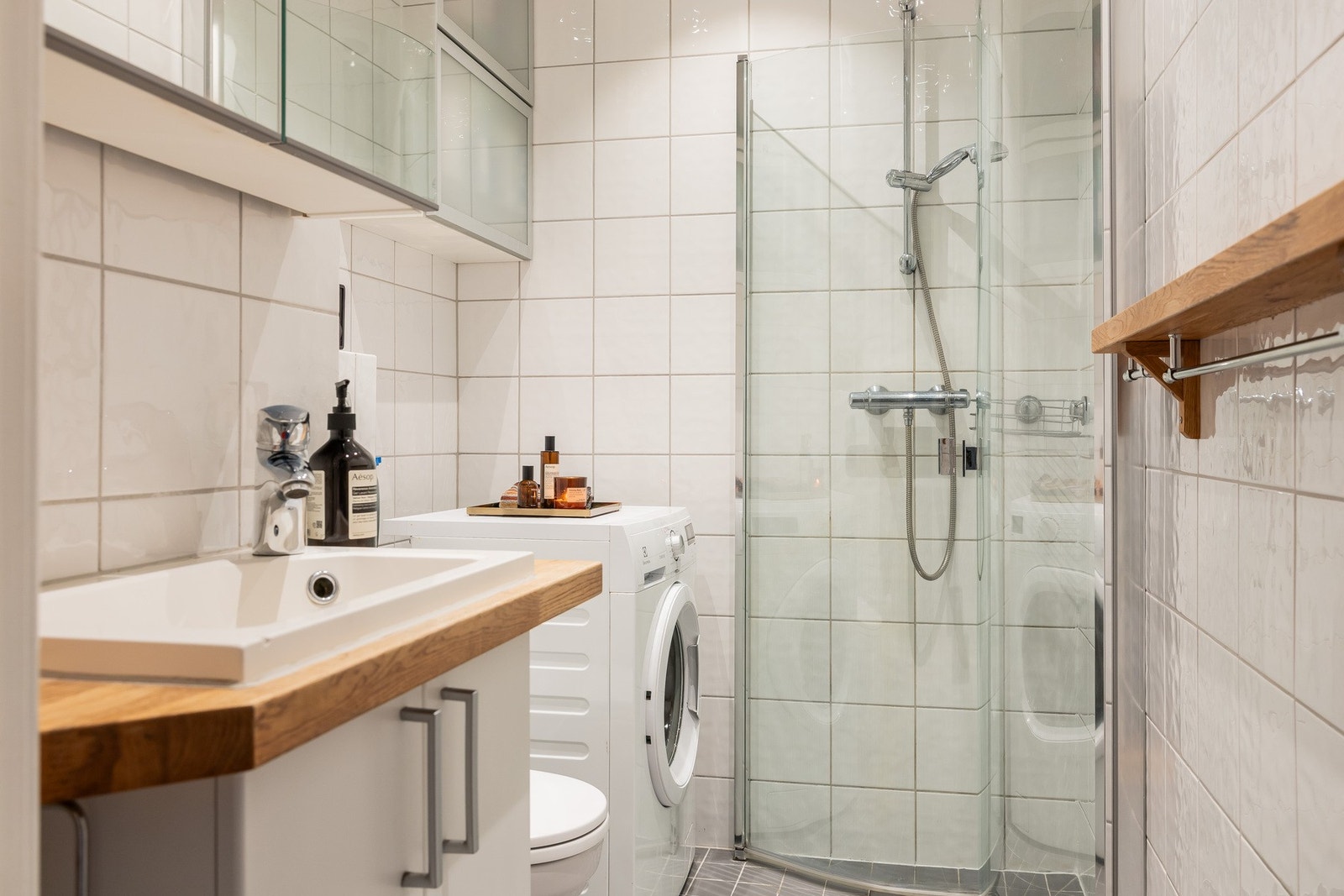 Flislagt bad med dusjnisje med innfellbare dusjdører, servant med ett greps blandebatteri og vegghengt toalett. Galleribilde