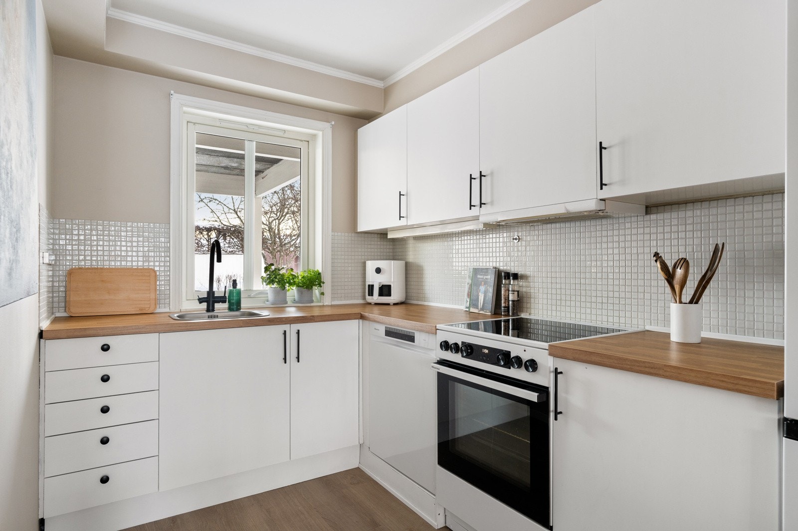 Kjøkkenet er praktisk L-formet for å få utnyttet plassen maksimalt. Her er det god plass for å tilberede ulike måltider, samt oppbevaring i skuffer og skap. Kjøkkenet inneholder komfyr, oppvaskmaskin og frittstående kjøleskap som alle medfølger handelen. Galleribilde