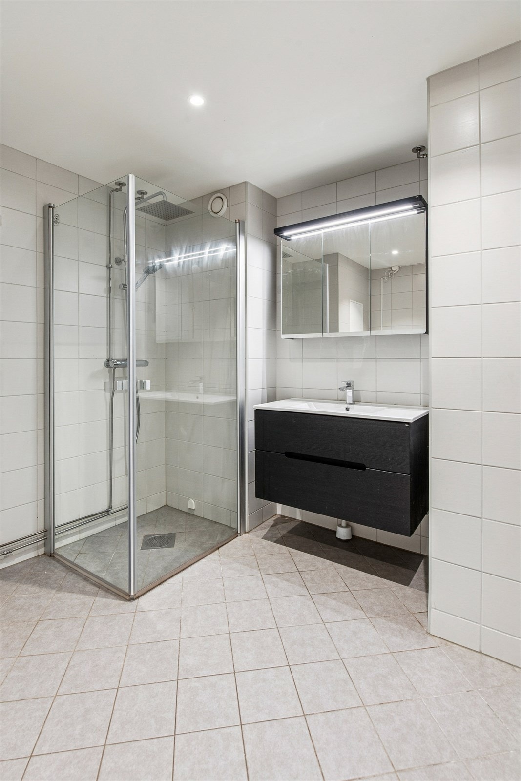 Dusjhjørne med innfellbare glassdører og elektriske varmekabler i det flislagte gulvet. Galleribilde