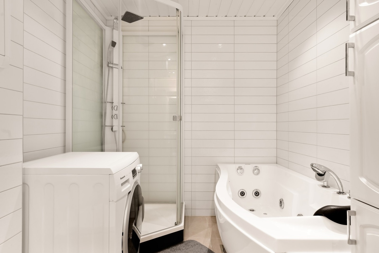 Rommet har innredning med to nedfelte servanter, veggfestet toalett, dusjkabinett, massasjebadekar og opplegg for vaskemaskin Galleribilde