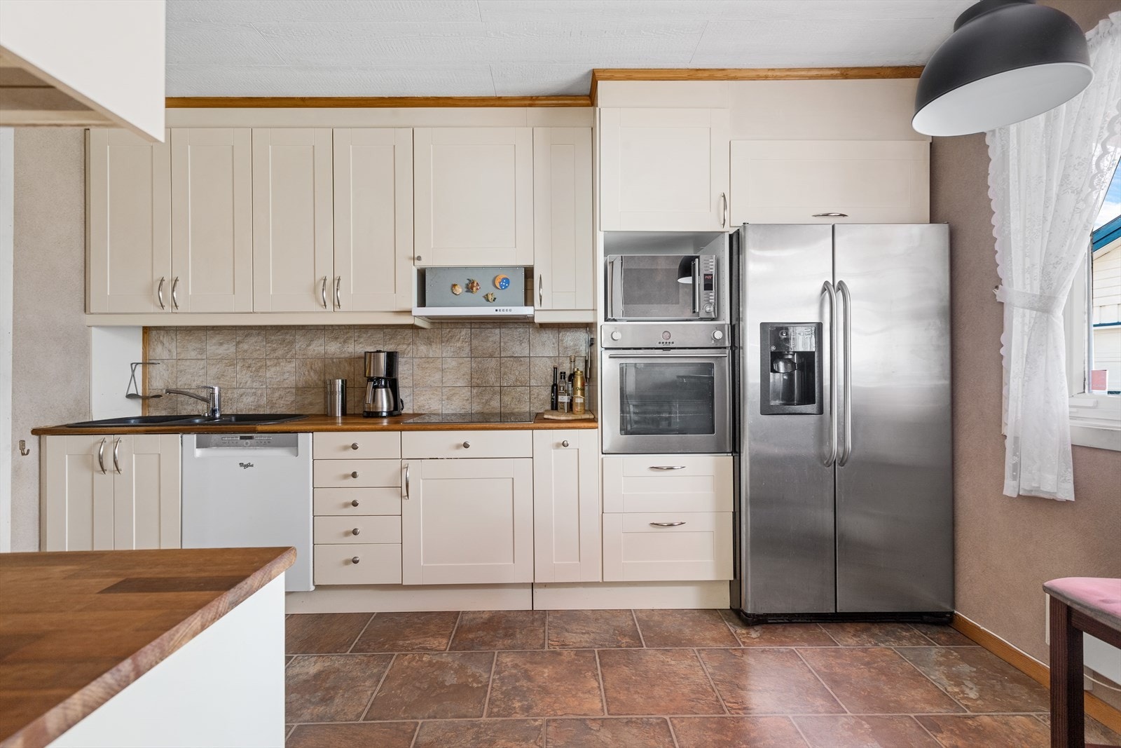 Kjøkkeninnredning med integrert stekeovn og platetopp samt heltre benkeplate Galleribilde