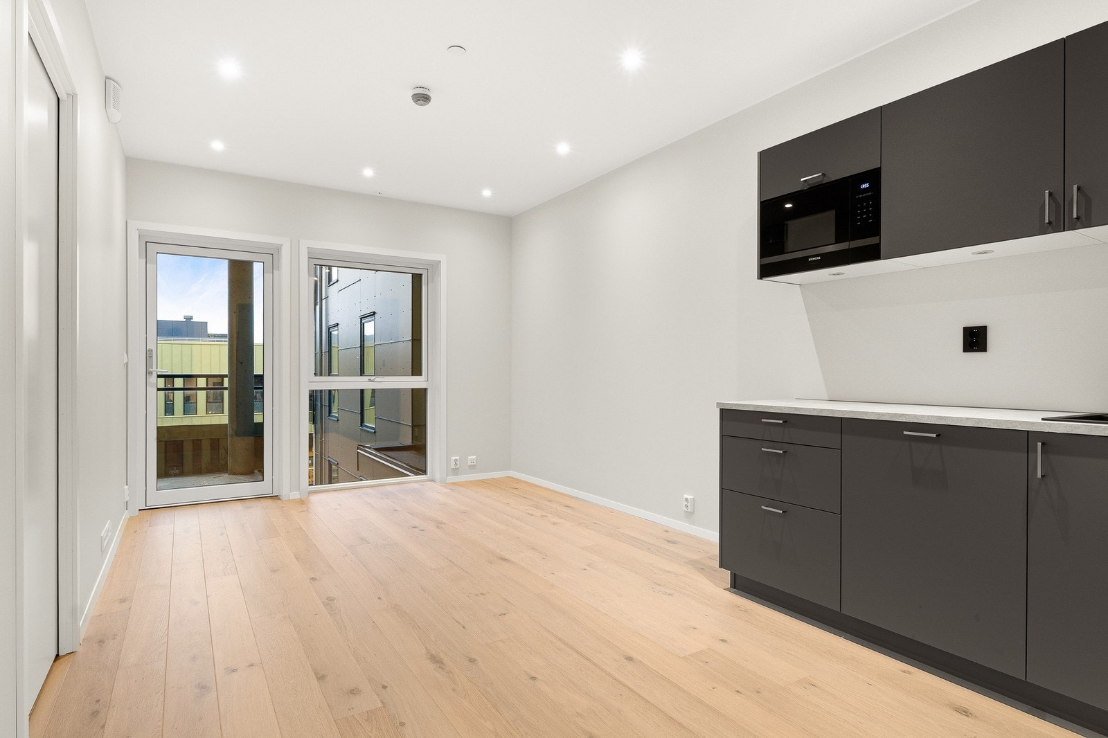 Lys og moderne stue i åpen løsning med kjøkken. God plass til å møblere opp med spisebord og sofa. Galleribilde