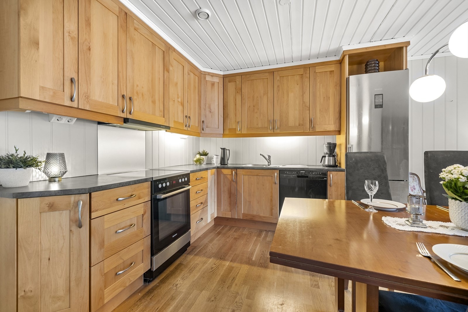 Innredningen framstår klassisk med profilerte fronter, laminat benkeplate og belysning under overskap. Galleribilde