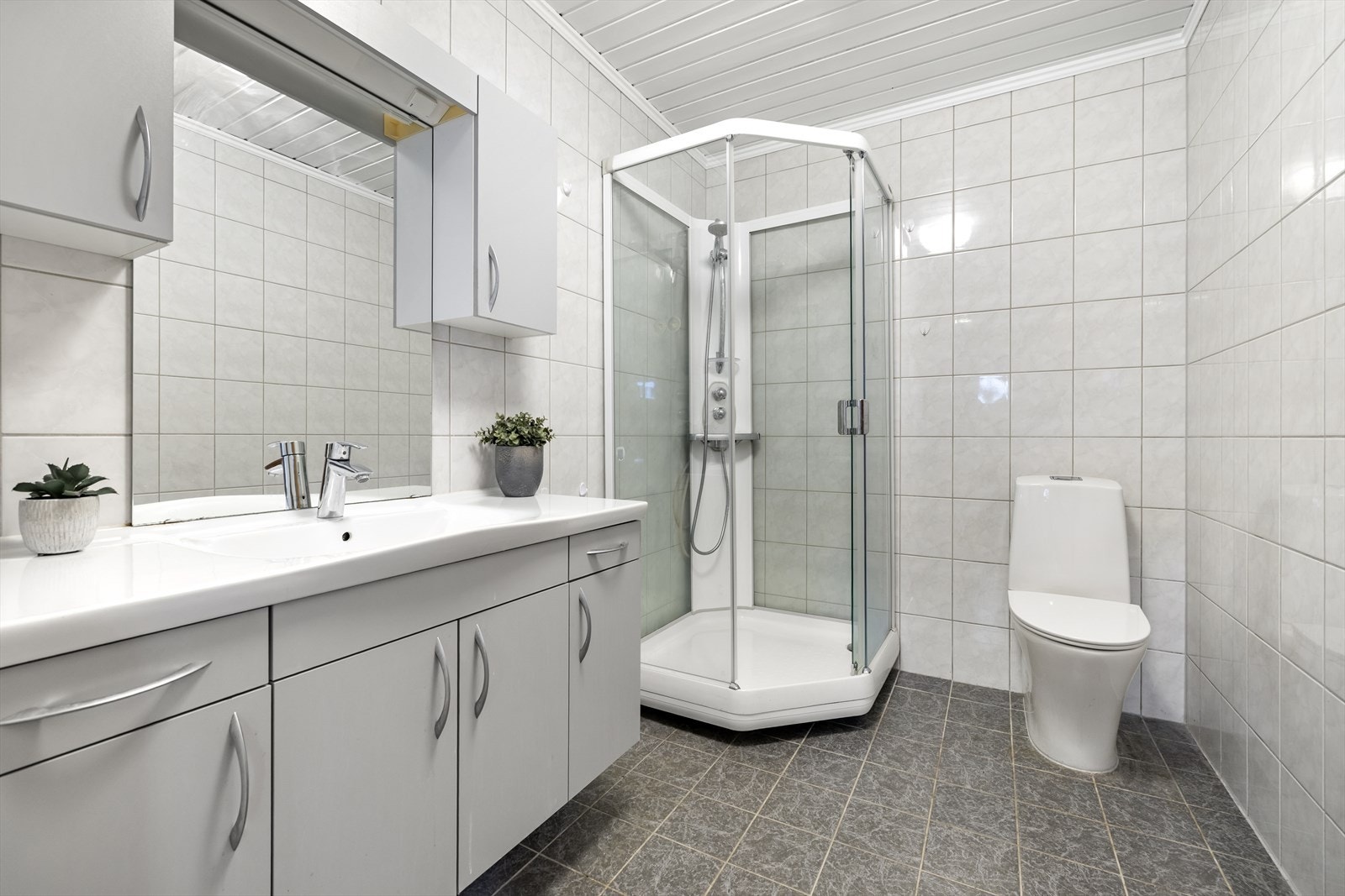 Baderom med flislagte gulv og vegger i tidløse fargetoner. Galleribilde