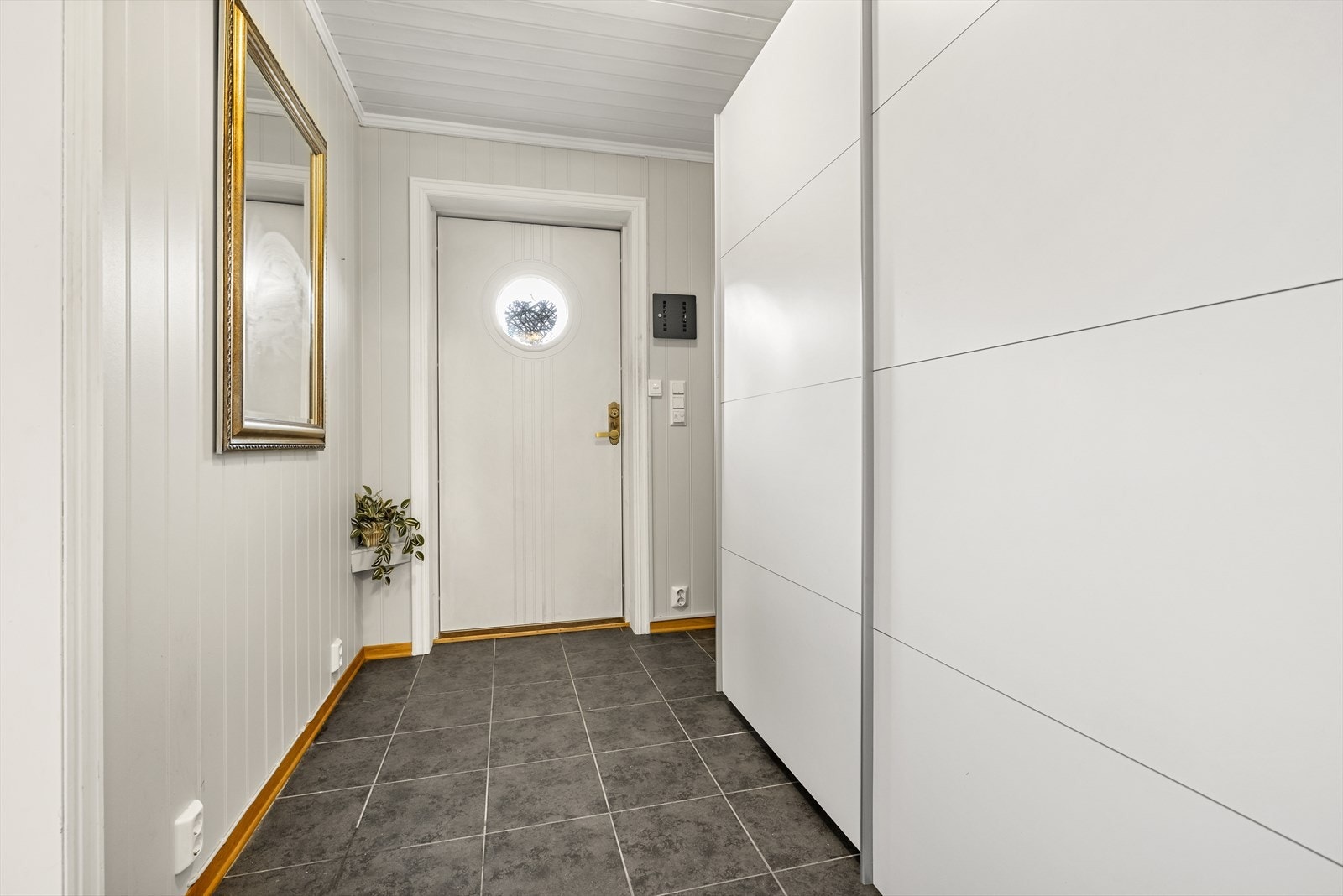 Lys entré med flislagt gulv og panelte overflater. Galleribilde