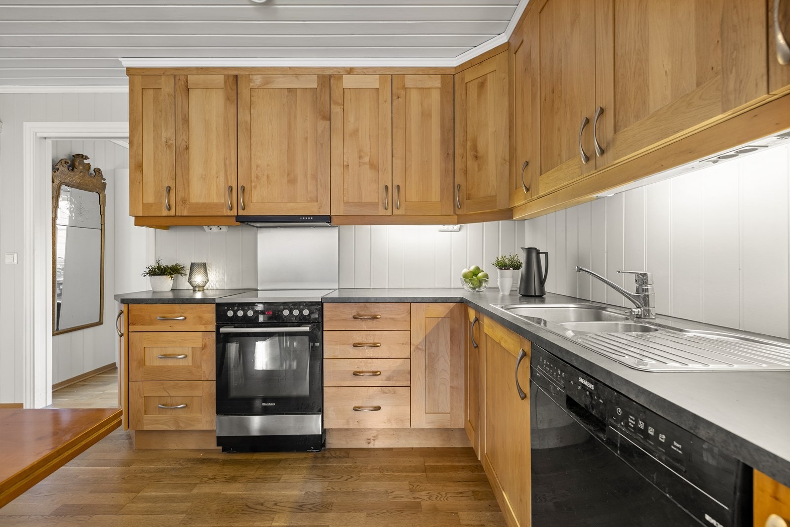 Frittstående hvitevarer som komfyr, oppvaskmaskin og kjøleskap, samt takhøye overskap. Galleribilde