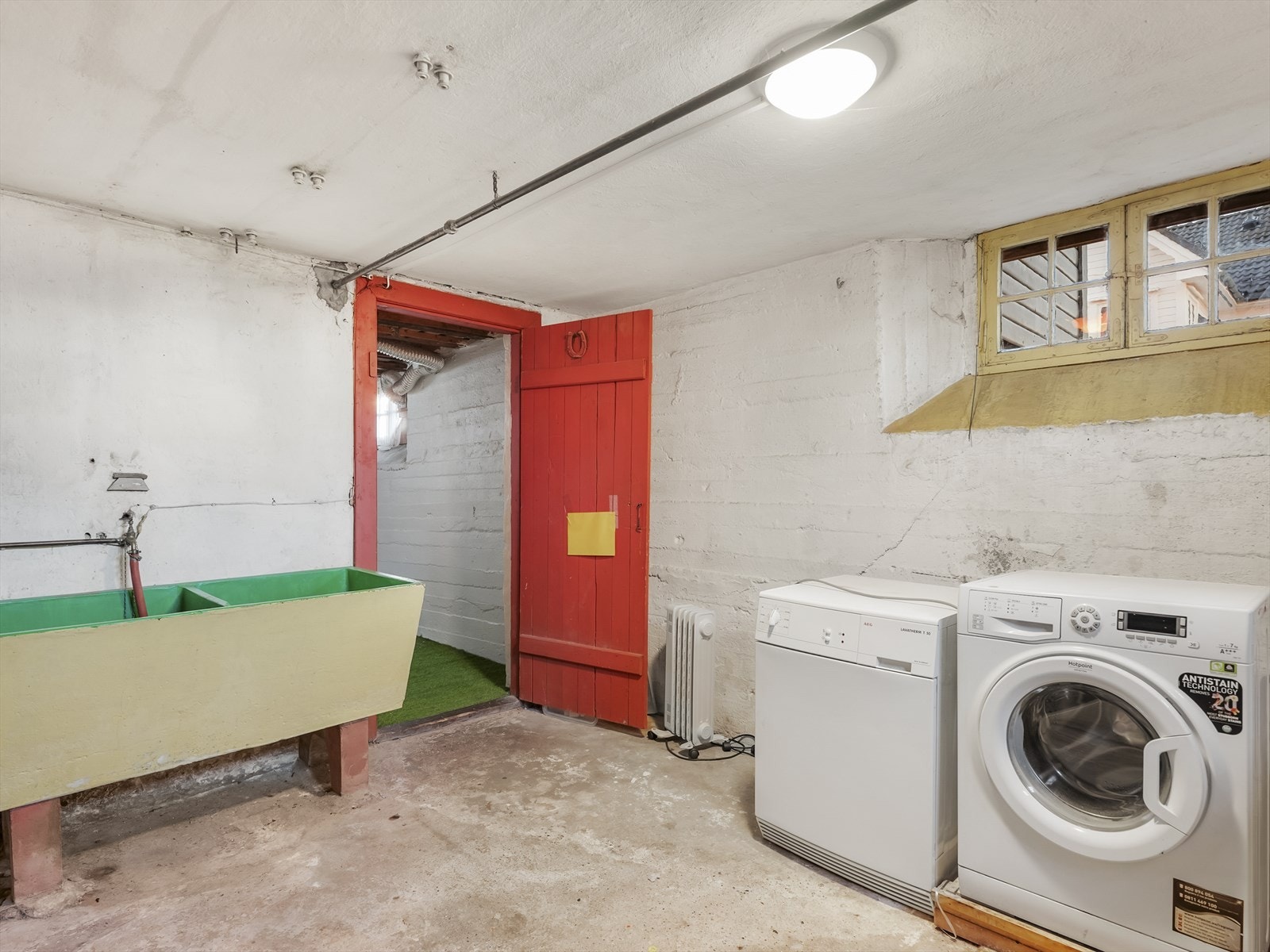 Vaskerom i kjeller med opplegg for vaskemaskin og en eldre skyllekar i betong. Galleribilde