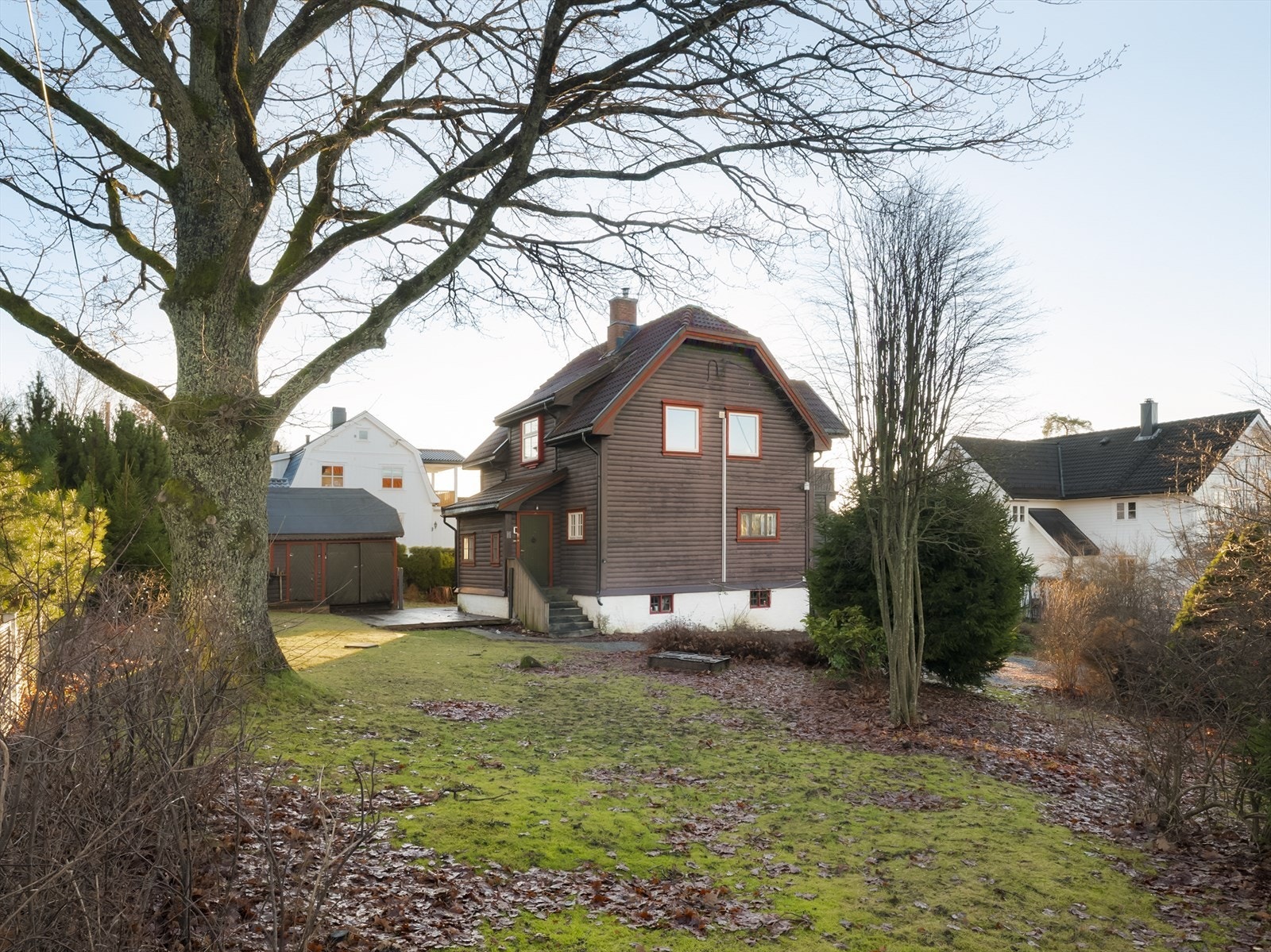 Boligens bakside med utsyn over hagen og den frittstående uteboden. Galleribilde