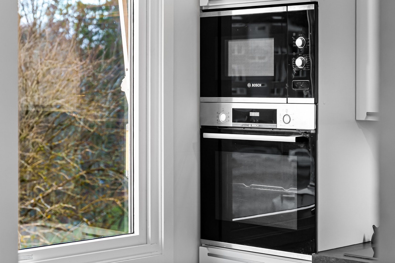 Integrerte hvitevarer gir et pent og helhetlig inntrykk; induksjonsplatetopp, stekeovn, mikrobølgeovn, oppvaskmaskin og kjøle/fryseskap. Galleribilde